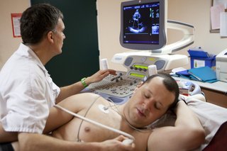 En mand med et ekkokardiogram med sensorer fastgjort til brystet og et billede på en skærm